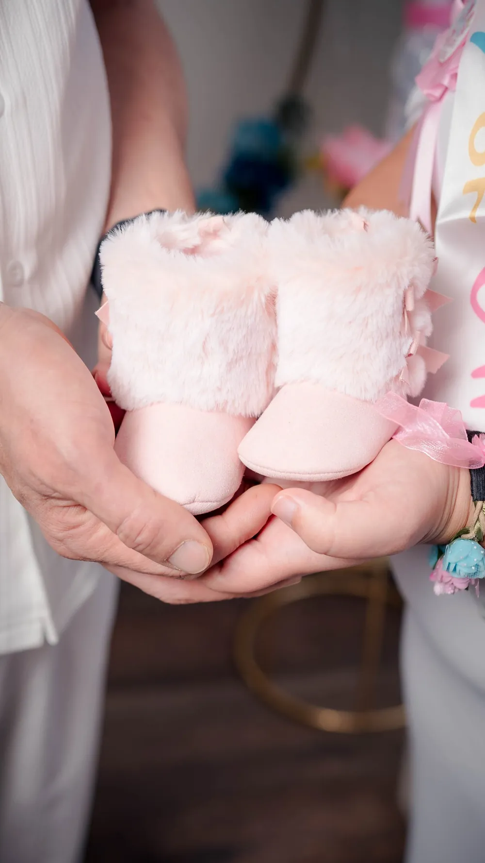 Parents holding pink baby booties